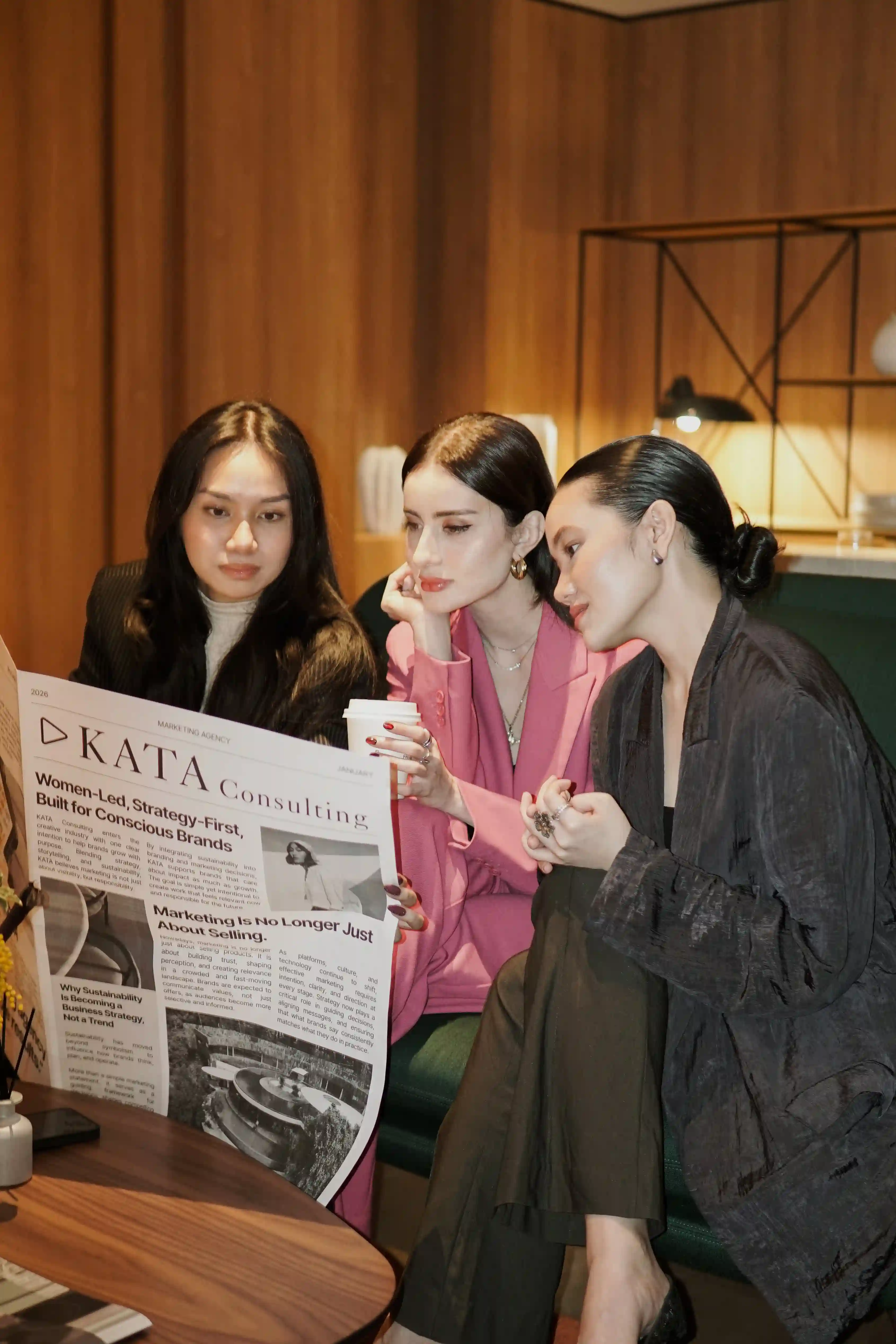 Three KATA team members seated together for a portrait under a pendant light